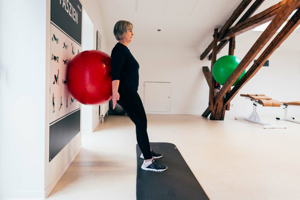 Startposition Kniebeuge an der Wand mit Gymnastikball Startposition Kniebeuge an der Wand mit Gymnastikball