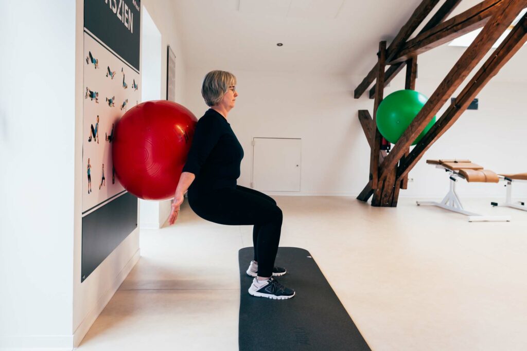 Endposition Kniebeuge an der Wand mit Gymnastikball